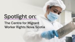 Graphic featuring the text “Spotlight on: The Centre for Migrant Worker Rights Nova Scotia.” Beside the text, a person wearing a hairnet, face mask, and gloves works with a large knife in a food-processing environment.