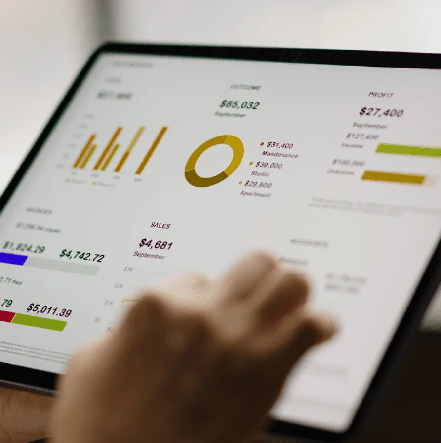 Une personne tient une tablette affichant diverses visualisations de données, notamment des graphiques à barres, un graphique circulaire et des graphiques linéaires, représentant des analyses financières ou commerciales.