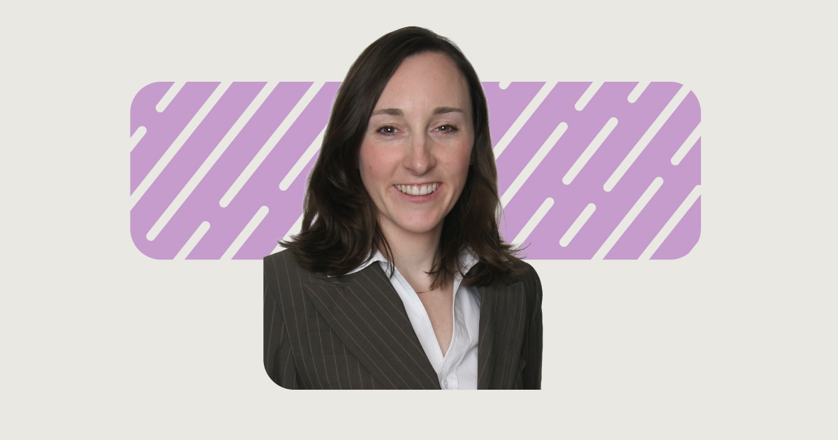 A person with long brown hair wearing a pinstripe blazer and white shirt is smiling. The background features a purple rectangle with diagonal white lines on an off-white backdrop.